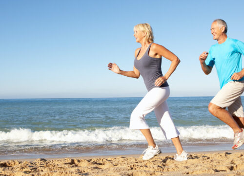 Photo of an older couple running on the beach