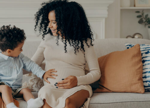 Photo of a pregnant mom sitting on the sofa with her young son